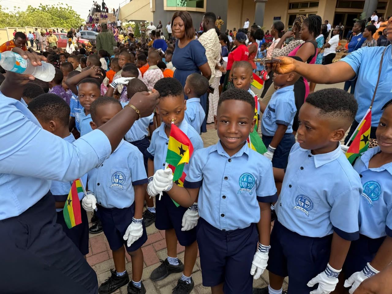 Regina Mundi pupils in school uniform waving Ghana flags at a school event